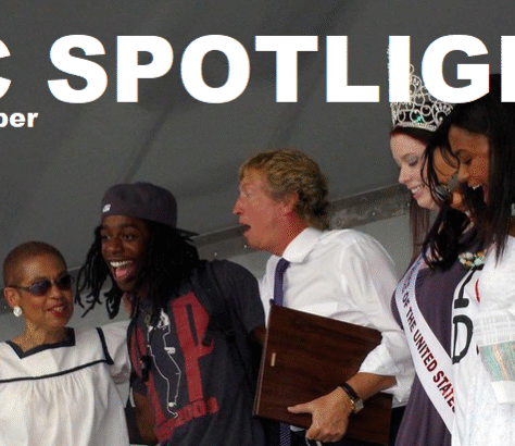 A group of people smiling and celebrating on stage with a spotlight above.