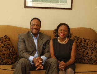 A man and woman sitting on a couch, smiling at the camera.
