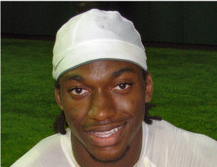 A smiling athlete wearing a white cap and sports attire.