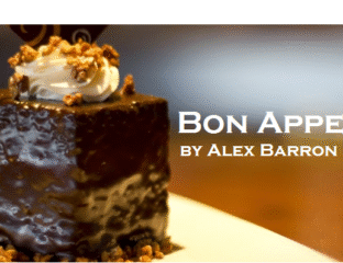 A glossy chocolate dessert topped with whipped cream and nuts.