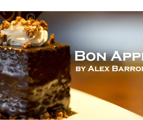 A glossy chocolate dessert topped with whipped cream and nuts.