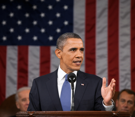 Barack Obama delivering a speech in front of an American flag.