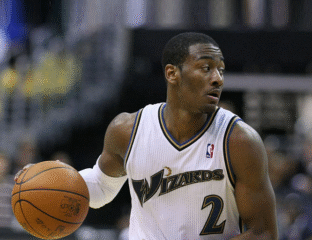 Basketball player in white Wizards jersey dribbling the ball on court.
