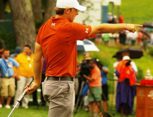 Golfer in orange shirt pointing on the course.