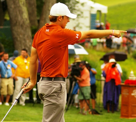Golfer in orange shirt pointing on the course.