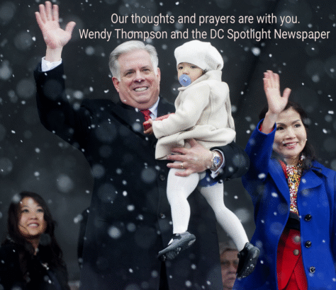 A group of people waving amidst falling snow with a man holding a baby.