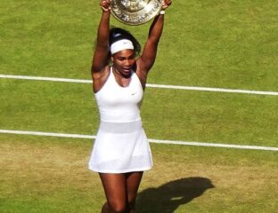 Tennis player celebrating with a trophy on a grass court.