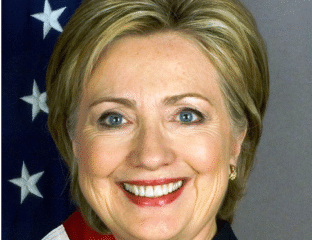 Portrait of a smiling woman with blonde hair and American flag background.