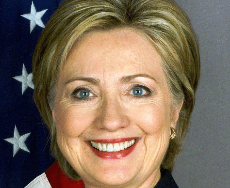 Portrait of a smiling woman with blonde hair and American flag background.