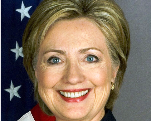 Portrait of a smiling woman with blonde hair and American flag background.