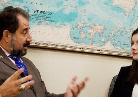 Two people in discussion beside a world map on the wall.