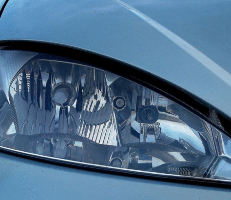 Close-up of a car's sleek headlight on a light blue body.