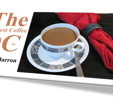 A cup of coffee on a saucer with a spoon, next to a red napkin.