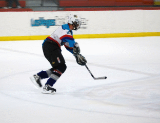 Ice hockey player skating and handling the puck on the rink.