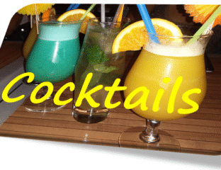 Three colorful cocktails with orange garnishes and straws on a wooden table.