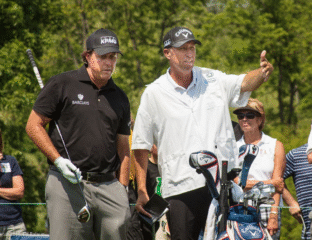Two men on a golf course, one giving instructions.