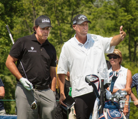 Two men on a golf course, one giving instructions.