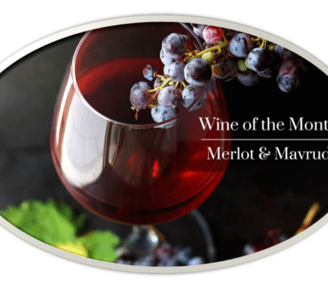 A glass of red wine with grapes, highlighting Merlot and Mav wine varieties.