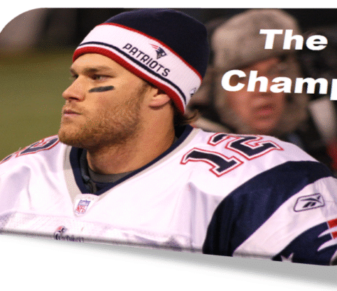 Tom Brady in a Patriots uniform looking determined on the sidelines.