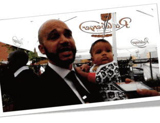 Man holding baby in front of a restaurant window.