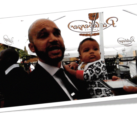 Man holding baby in front of a restaurant window.