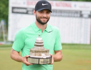 A smiling golfer in a green shirt holding a trophy shaped like the US Capitol.