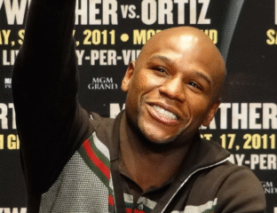 Smiling man at a press event with promotional text in the background.