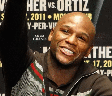 Smiling man at a press event with promotional text in the background.