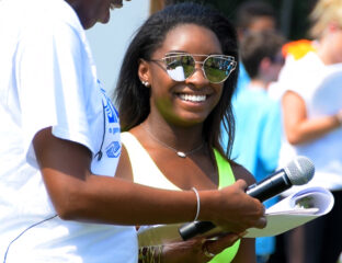 Smiling woman in sunglasses engaging in an outdoor event.
