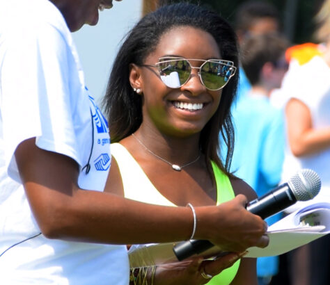 Smiling woman in sunglasses engaging in an outdoor event.
