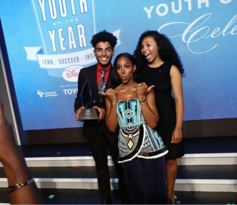 Three people posing on a stage at a Youth of the Year award event.