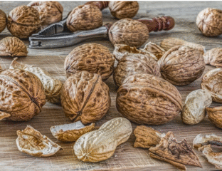 A close-up of whole walnuts and peanuts on a wooden surface.