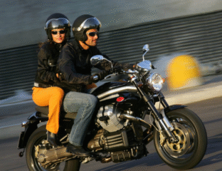 Two people riding a motorcycle wearing helmets and jackets.