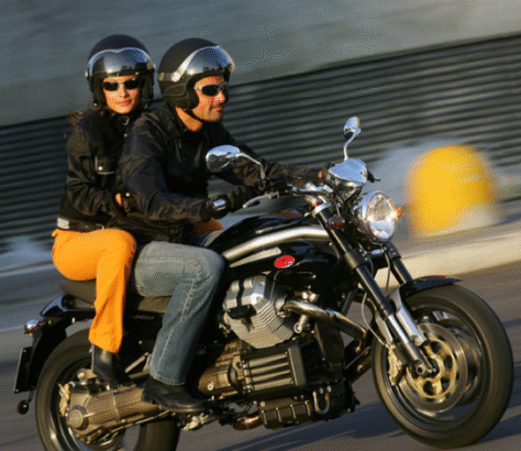 Two people riding a motorcycle wearing helmets and jackets.