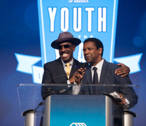 Two men speaking and smiling at a podium during an event.