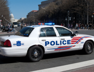Police car parked on a city street with lights on.
