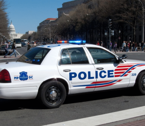 Police car parked on a city street with lights on.