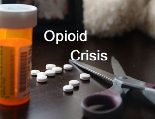 Scattered pills, scissors, and prescription bottle highlighting opioid crisis.