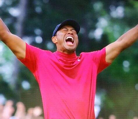 Tiger Woods celebrating a golf victory with arms raised.