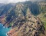 Aerial view of rugged mountains with lush greenery and a rocky coastline.