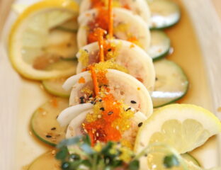 Elegant scallop dish garnished with lemon slices and herbs.