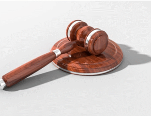 A wooden judge's gavel resting on a sound block.