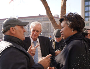 Three people engaged in a serious conversation outdoors.