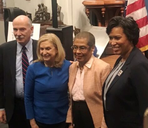 Four diverse professionals posing together indoors.