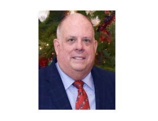 Portrait of a middle-aged man in a suit and red tie with a festive background.