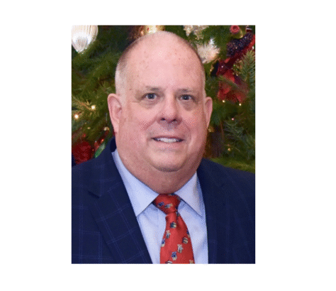 Portrait of a middle-aged man in a suit and red tie with a festive background.