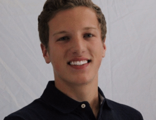 Young man smiling in a black polo shirt against a plain background.