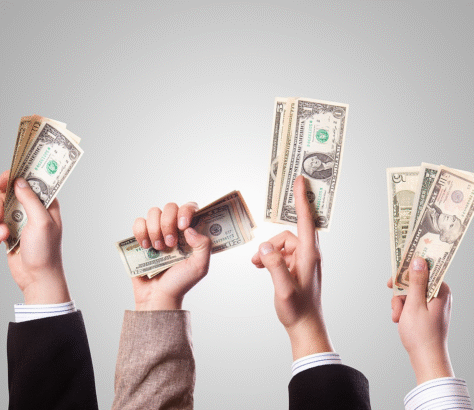 Hands holding and raising US dollar bills in celebration or demand.