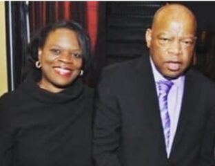 A smiling woman and a serious man posing together indoors.