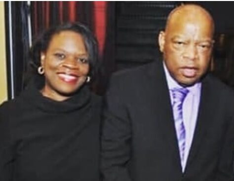 A smiling woman and a serious man posing together indoors.